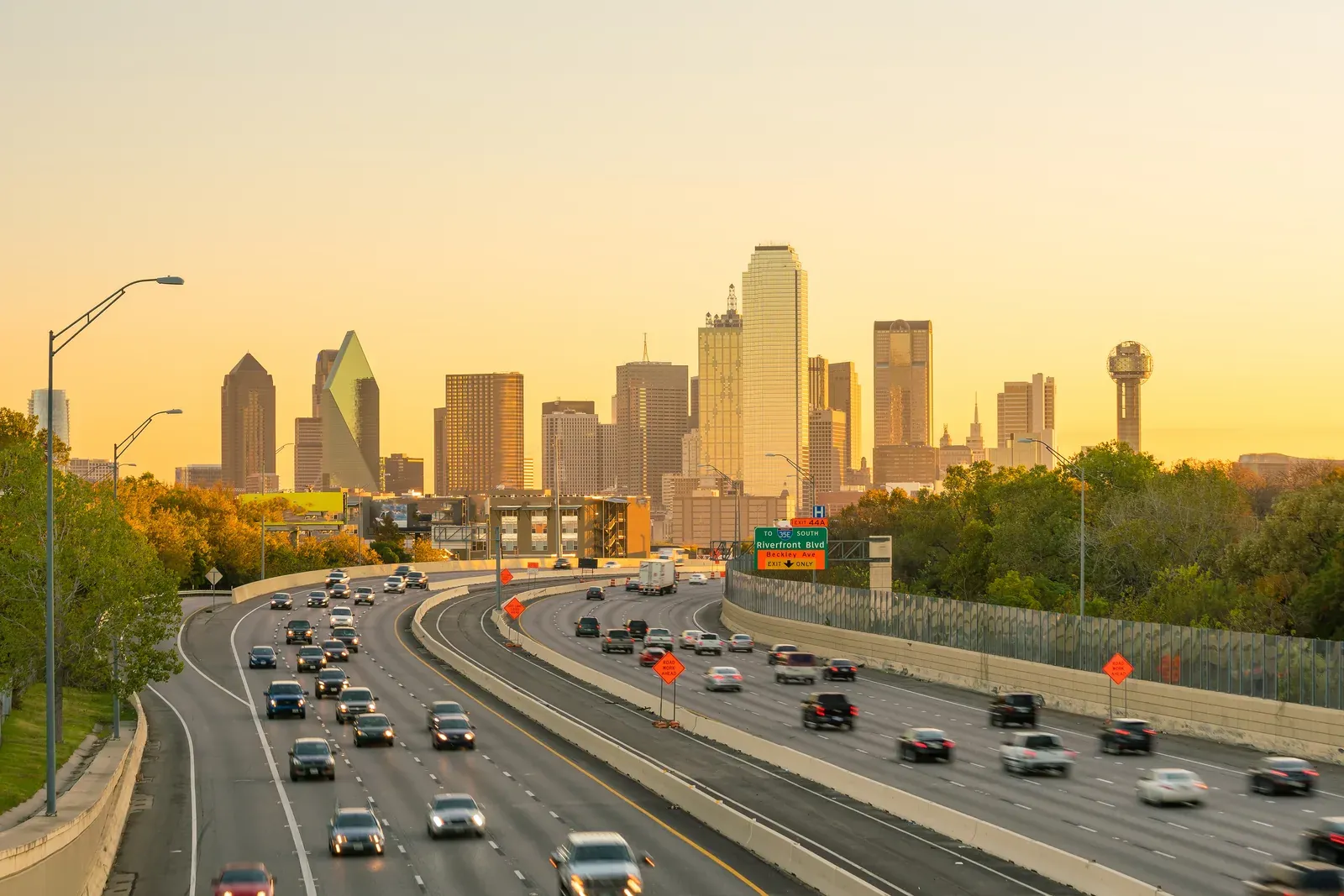 The Dallas skyline at sunset above the highway running into the Metroplex