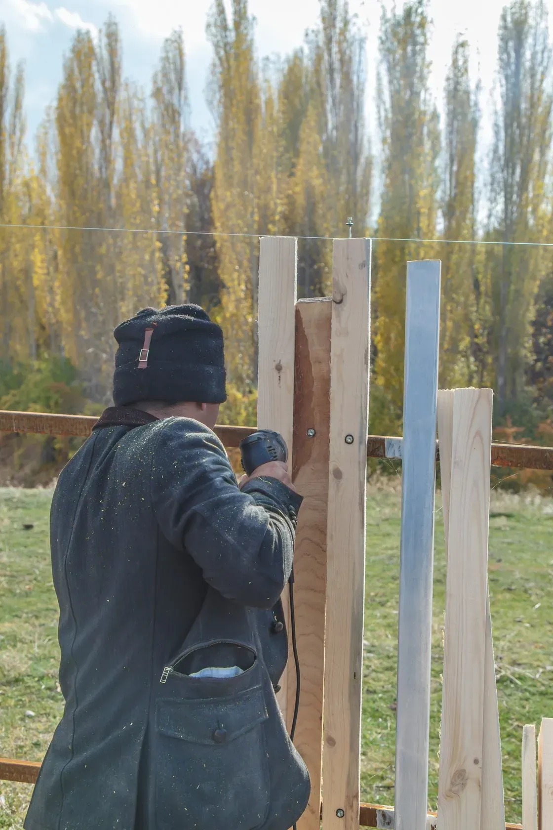 A fencing crew installing cedar fence panels along a residential property line