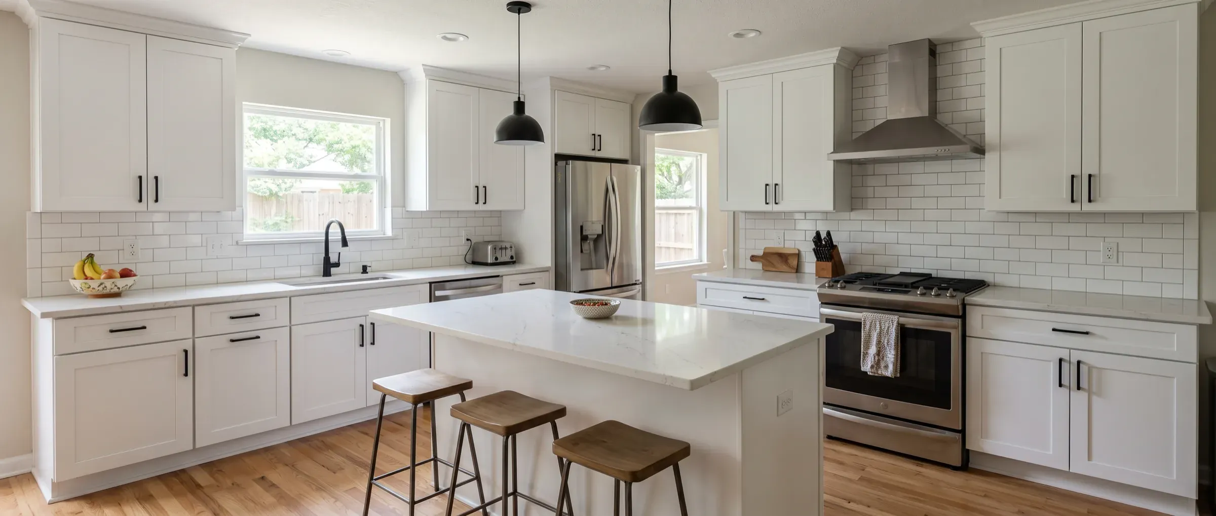 A finished kitchen remodel with white shaker cabinets, quartz countertops, a center island with three stools and oak floors