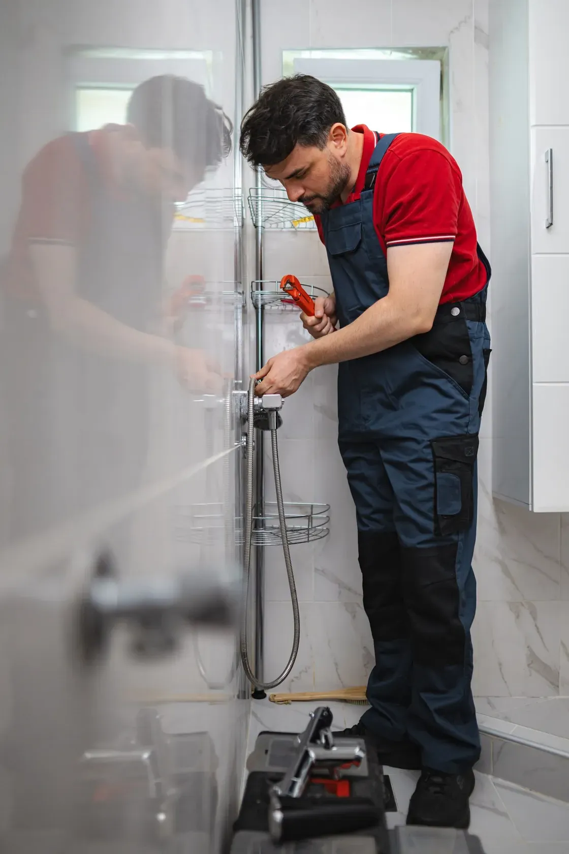 A plumber repairing a shower valve inside a customer's bathroom