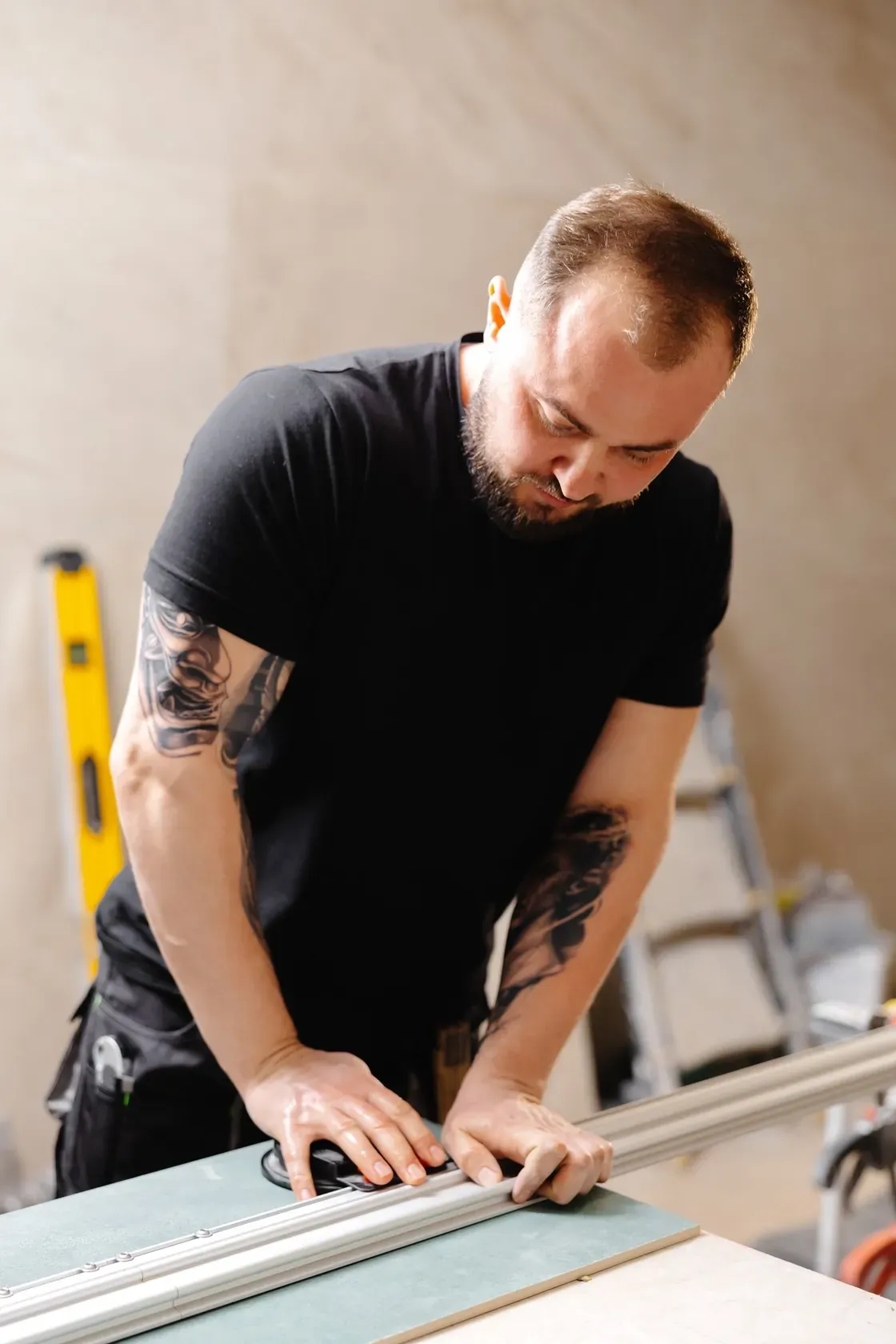 A remodeler measuring and marking a wall in a partially finished room